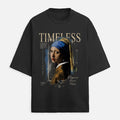 A black short-sleeve t-shirt featuring a graphic print of Johannes Vermeer's 'Girl with a Pearl Earring' styled with blueprint elements and the word 'TIMELESS' in beige text, shown against a light gray background.